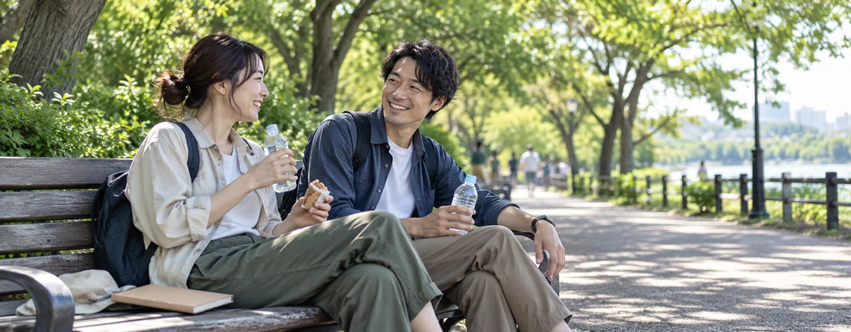 公園のベンチで水分をとりながら休憩する2人