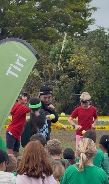 TekXYZ founder demonstrating a boxing reflex ball in front of children gathered at a school event.