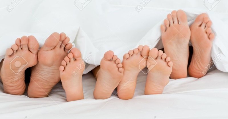 10195547-ベッドの上_自宅で自分の足を示す家族