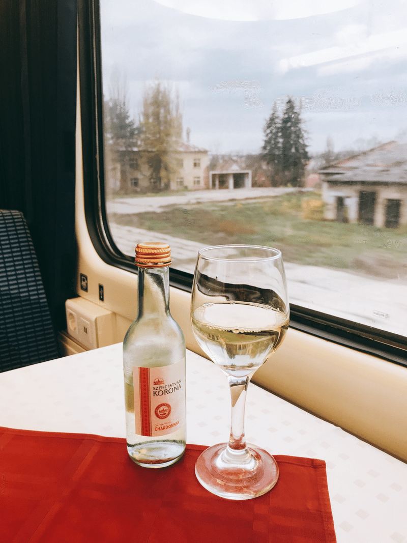 高速列車の食堂車の座席と車窓からの景色。座席の机にはワインが置かれている