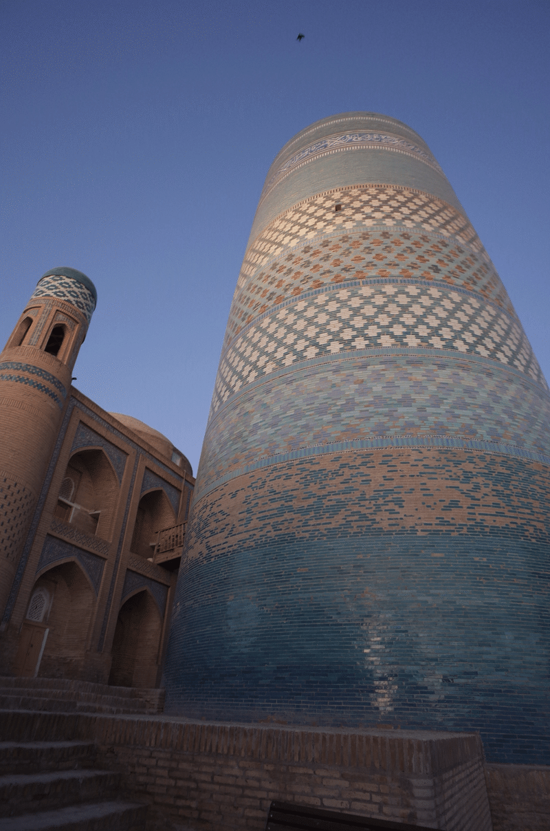青色などのタイルで覆われた円柱型の建物。朝の薄明かりに照らされている