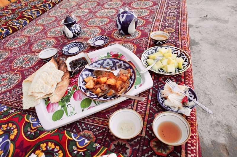 絨毯の上に複数の料理と、お茶の湯呑みとポットが置かれている