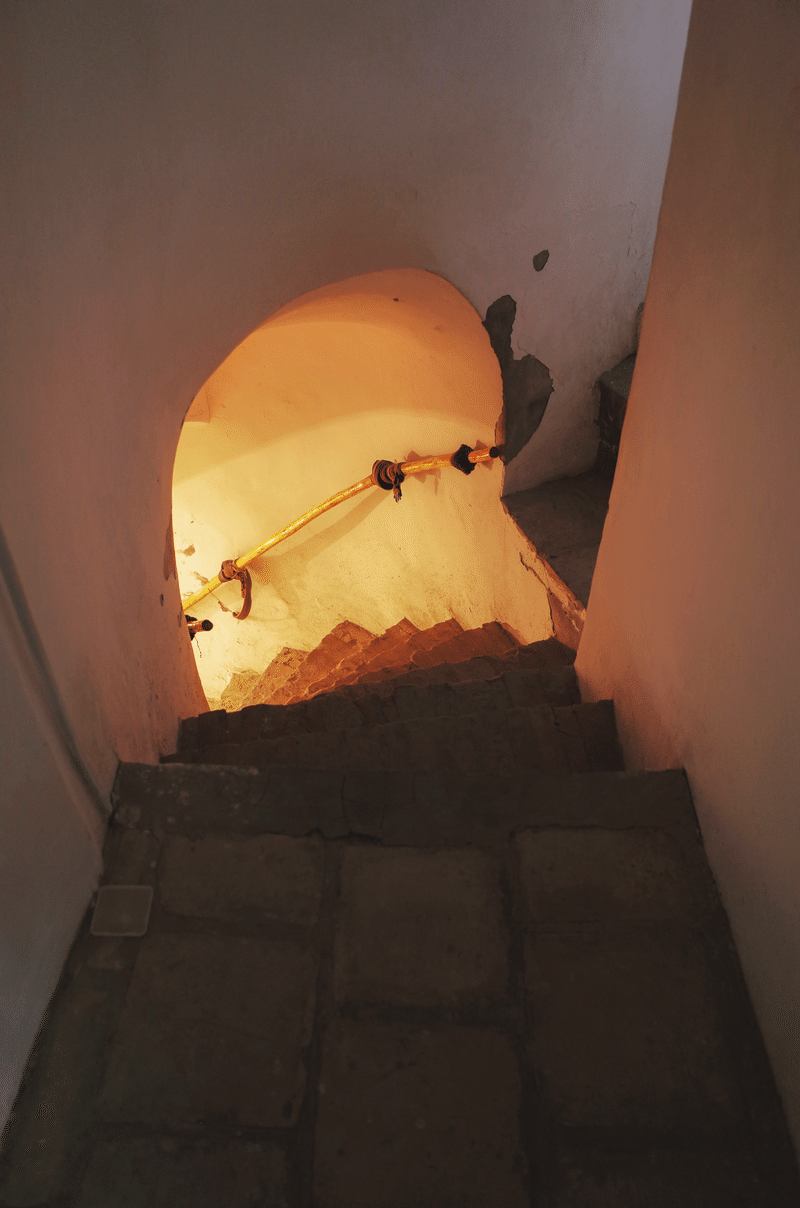 建物の中の階段。下の階からは温かなオレンジ色の光が差し込んでいる