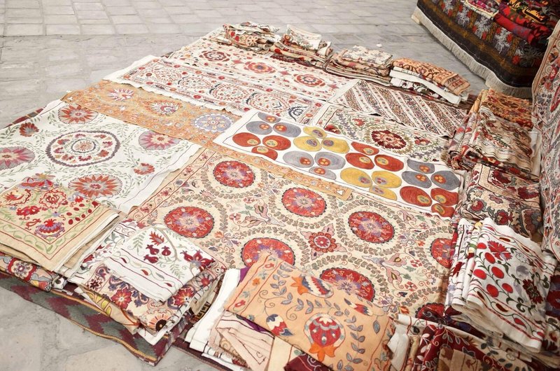 さまざまな柄の刺繍が施された布が床に並べられている様子