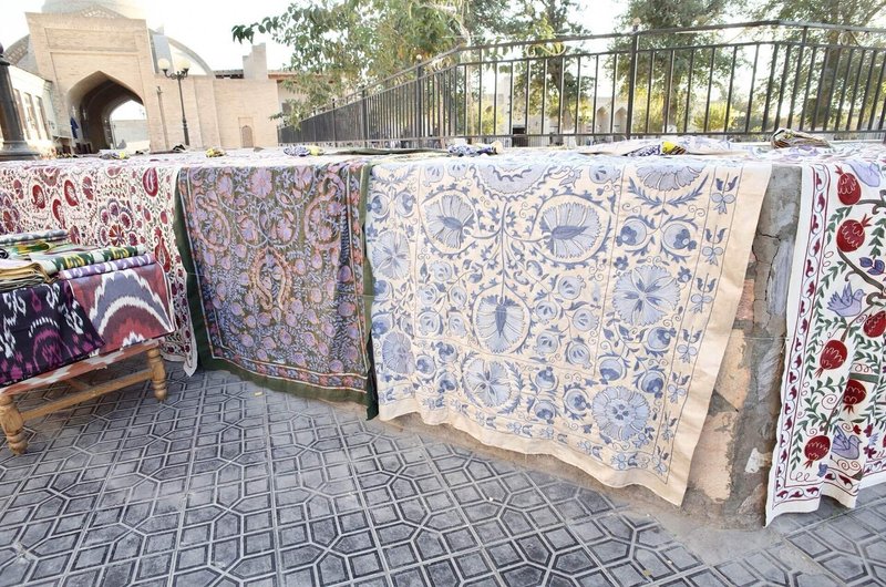 高めの段差に刺繍が施された大きな布が複数並べられている様子