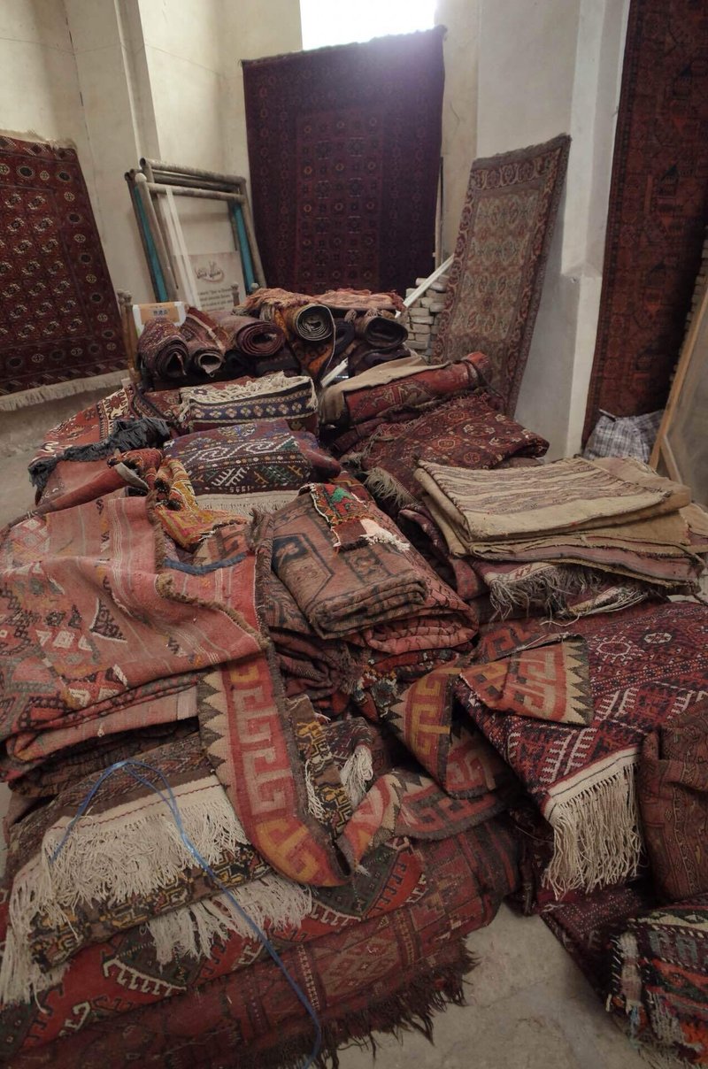 床の上に雑多に重ねられたたくさんの古い絨毯