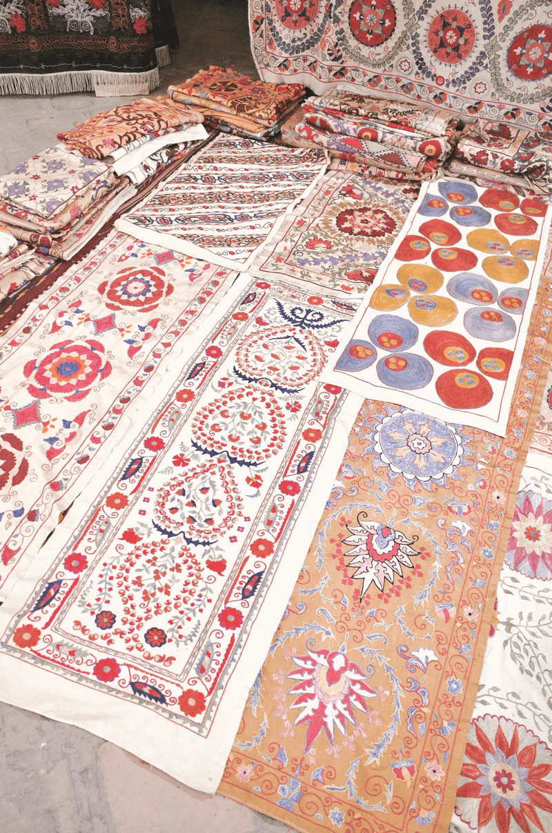 さまざまな柄の刺繍が施された布が床に並べられている様子