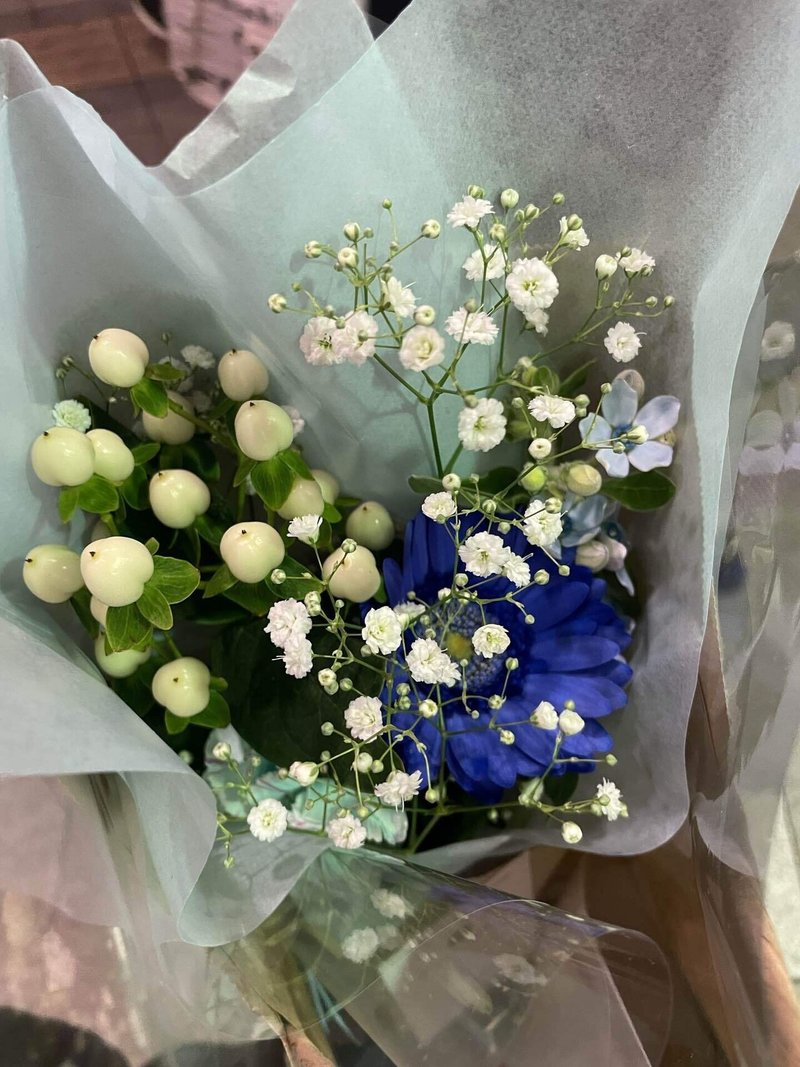 青いガーベラ、しろい勿忘草、白い実などで構成された花束