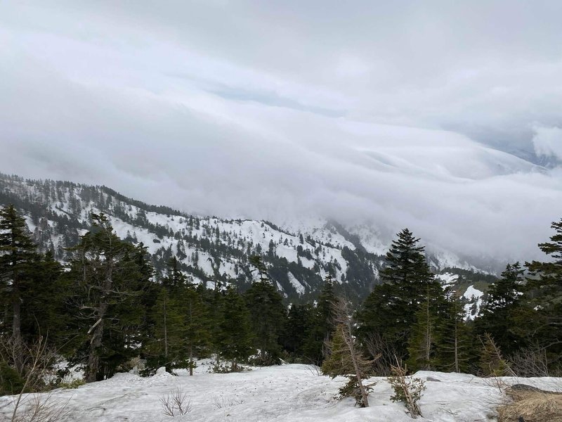 山の稜線に沿うように雲が立っている写真