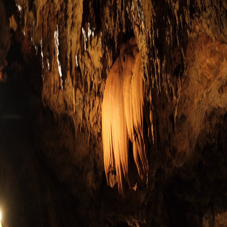 カーテン状に垂れ下がる赤と白の鍾乳石が神秘的な鍾乳洞
