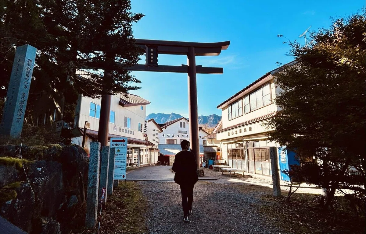 成就社の鳥居をくぐる夫