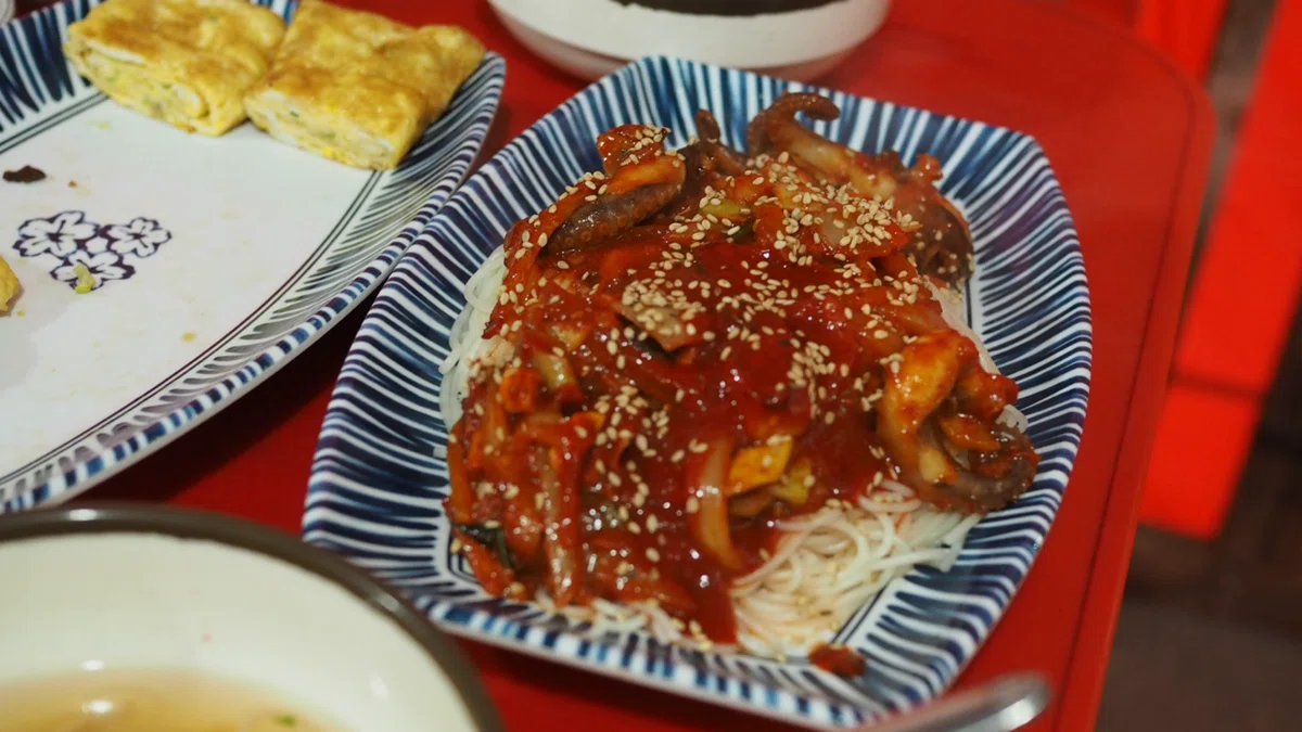 ひやむぎのような麺の上に乗せられた辛い炒め物