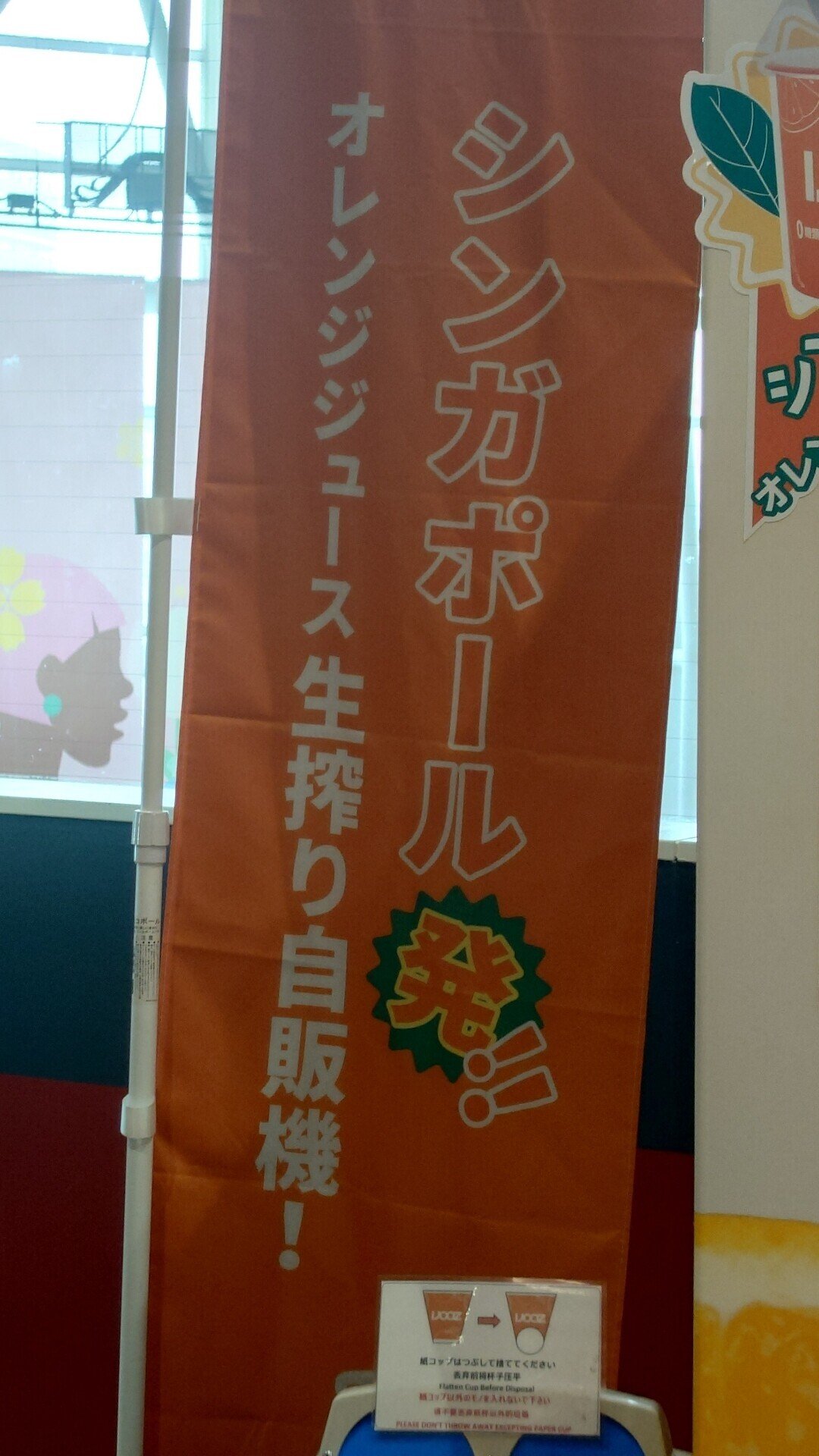 あのオレンジジュースの自販機の傍らにこんなのぼりが。シンガポール発って、そんなに惹かれるかな…？KJHR