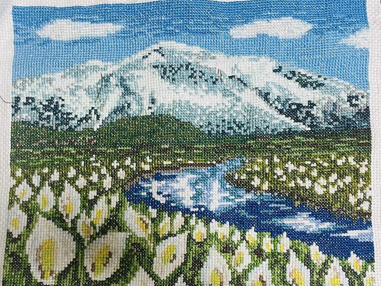 1年前から続けてきた刺繍。完成し額装。 雪の残る山並みを背負い