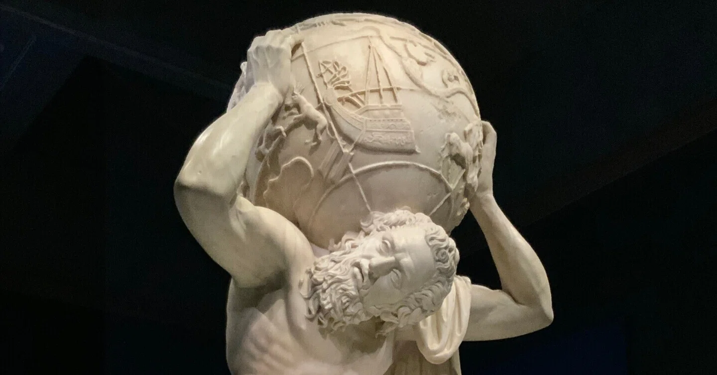 モダンアート 男性彫刻 球体の上に座る イギリス・ロンドンの建物の正面に、背中に球体を乗せた男の彫刻。写真