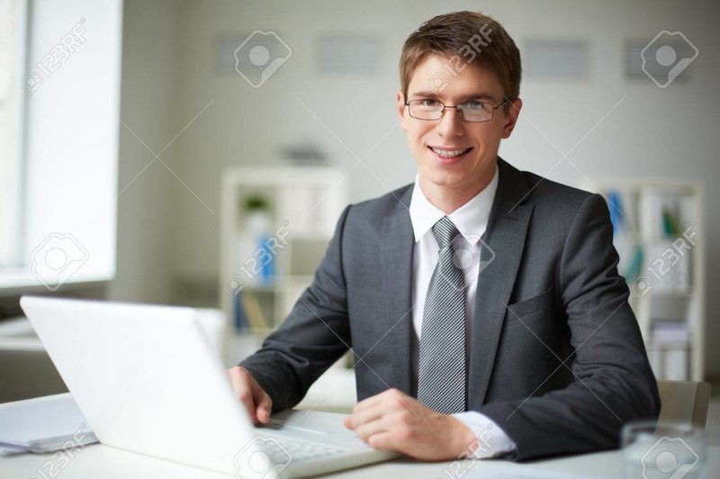 27241036-オフィスでノート-パソコンで作業のスーツのビジネスマンの笑みを浮かべてください。