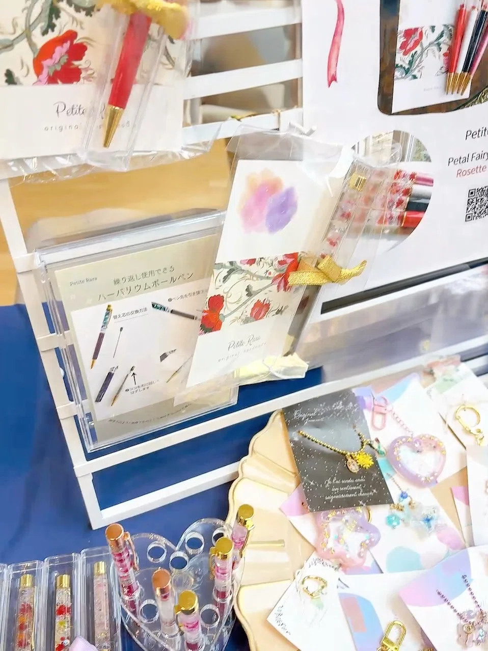 マルシェのPetite Raraブース。ハーバリウムボールペンやチェコガラスのアクセサリー、小さなキーホルダーなどのハンドメイド作品を並べて展示している様子。
