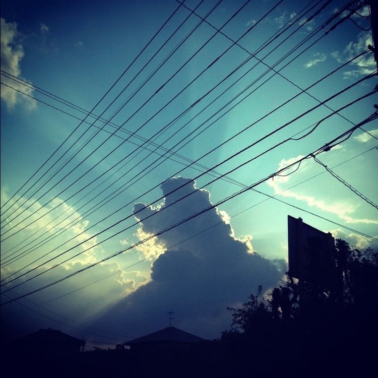 雲の裏に太陽が隠れ光の筋が放射している。まるで怪獣が空に向かって吠えているようだ。電線もその怪獣を捕らえているようだ。https://inagakijunya.wixsite.com/inagaki-junya-web/snap-001-100-1