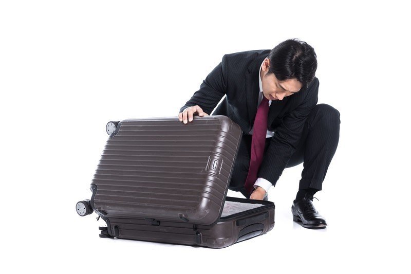 スーツケースを開ける男性