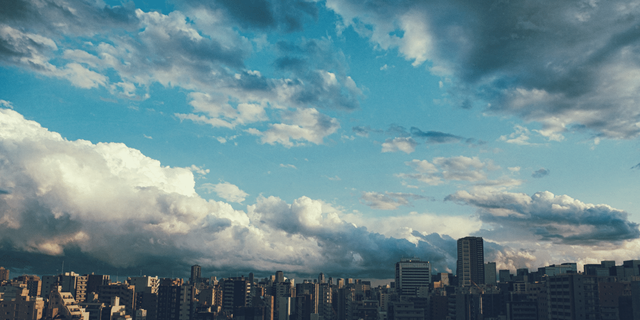 上空に晴れ間と雨雲の街並みのコピー