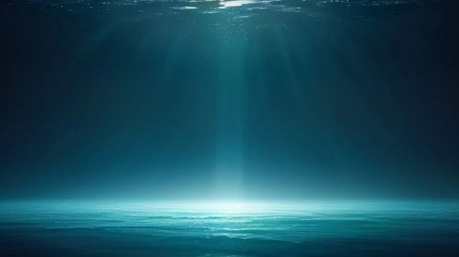 暗い海の中。水面から一本の光の柱がまっすぐ下りてきて、遠くの海底の面をぼんやり照らしている。青緑色の水が奥まで続き、生き物は一匹もいない