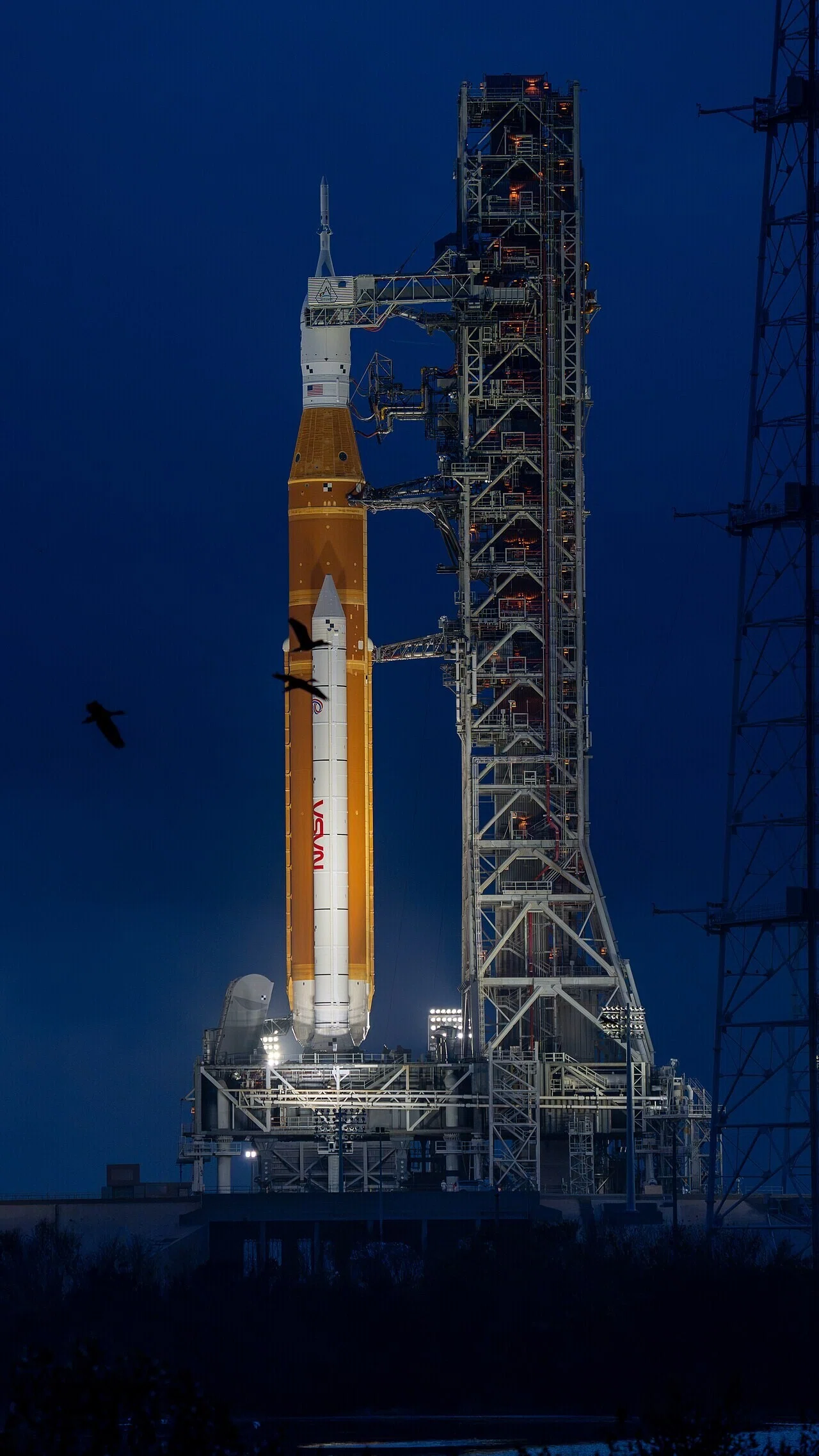 夕暮れの発射台39Bに立つSLSロケットとオライオン宇宙船。計画が実行段階へ進んだ姿を静かに印象づける。
