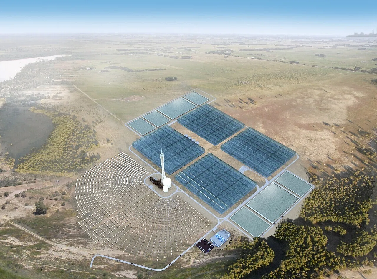 平地に広がる鏡のアレイと中央の塔からなる太陽光発電施設の空撮。再生可能エネルギーと農業の組み合わせを示す事例として注目できる。