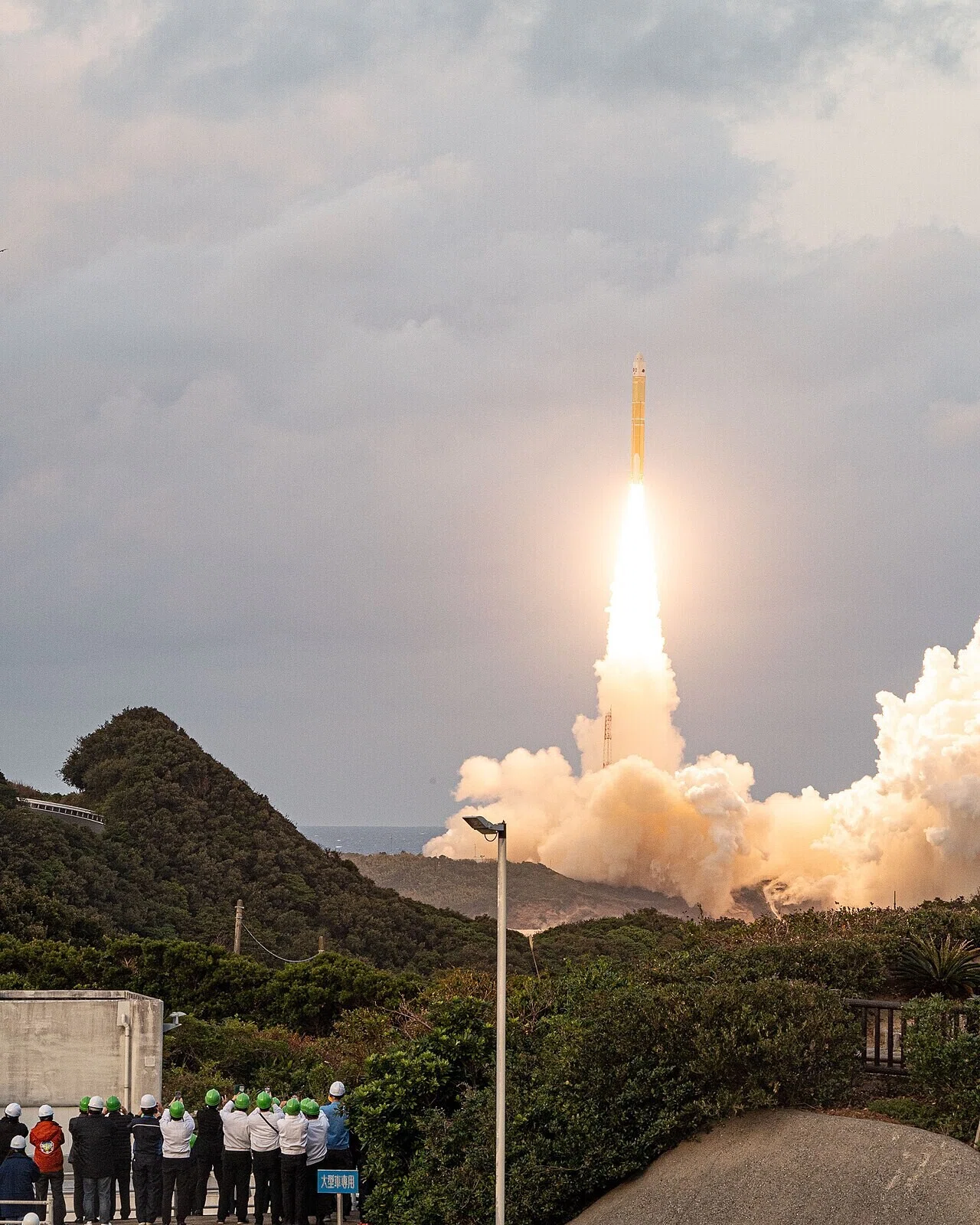 種子島で観衆が見守る中、H3ロケットが炎と煙を上げて打ち上がる様子。この打ち上げ成功が「危機的状況」からの脱却を示す実績として次節で語られる。