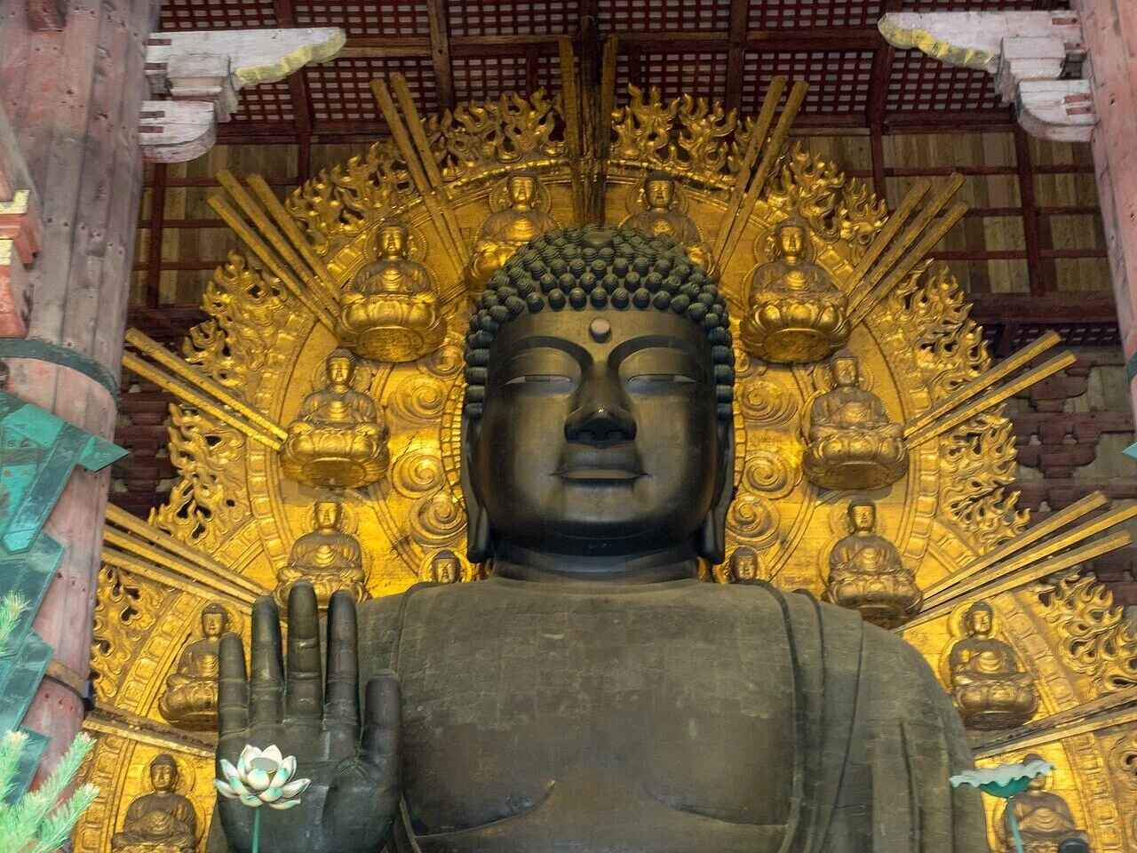 東大寺の堂内に安置された大きく手を上げた青銅の大仏像。金色の光背が荘厳な空気を漂わせ、奈良を代表する風景の一つだ。