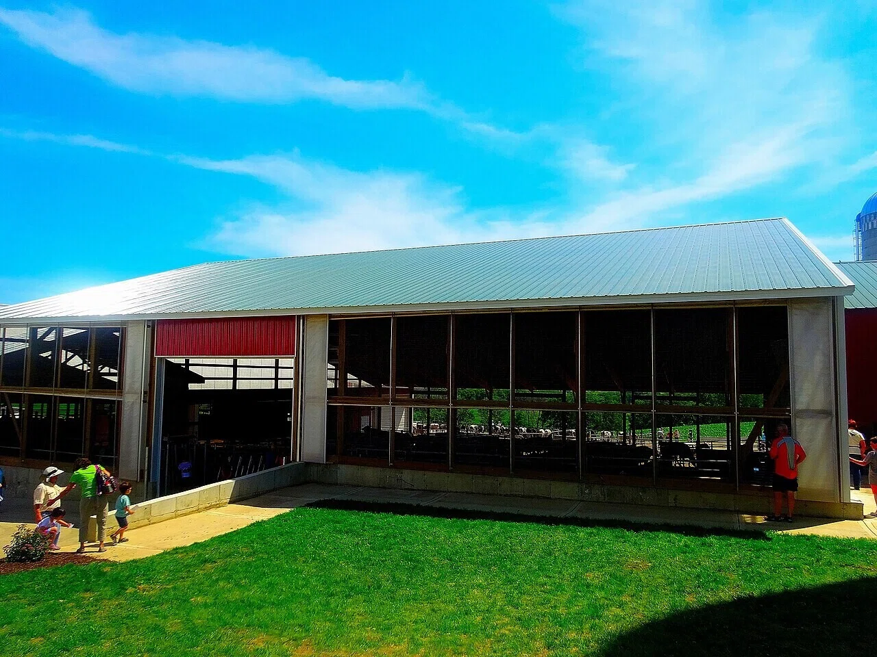A large open-style barn with a green roof and people walking around it. This image, showing the appearance of a livestock facility, serves as a review before proceeding to the glossary.