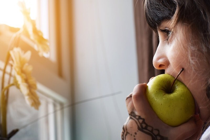 女性・リンゴ・食べる・咀嚼・窓の外を見る