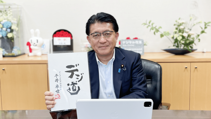 写真：平井卓也デジタル改革担当大臣が「デジ道」と書かれた紙を持っている