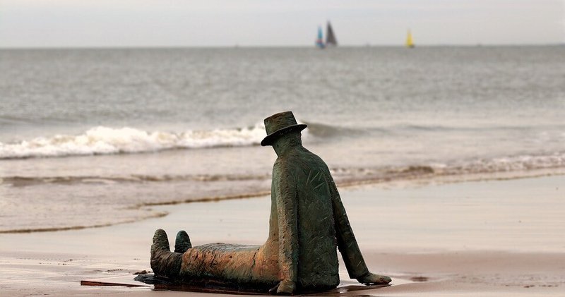 ビーチ・彫刻・男性の像・うなだれる・絶望・砂浜・打ちひしがれる
