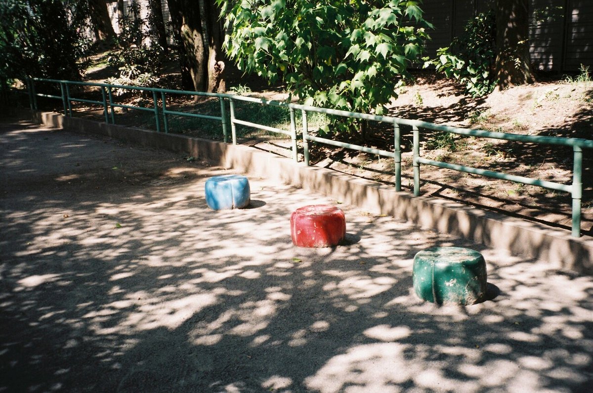 公園に置かれた青・赤・緑の丸いベンチのフィルム写真。