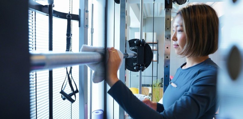 トレーニング器具を拭く女性パーソナルトレーナー