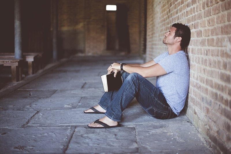 男性・壁にもたれかかる・読書・聖書・サンダル・目を閉じる