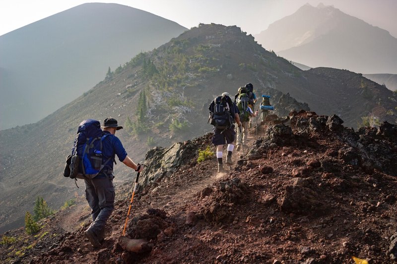 山の尾根を登っていく登山者たちの様子。遠景に山々が連なる。