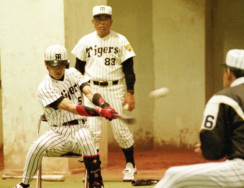 座ってティーバッティングに挑む新庄剛志、後ろは山内一弘コーチ（９５年５月、甲子園球場）