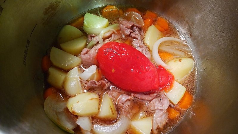 具材と調味料が入った鍋にトマトを入れる