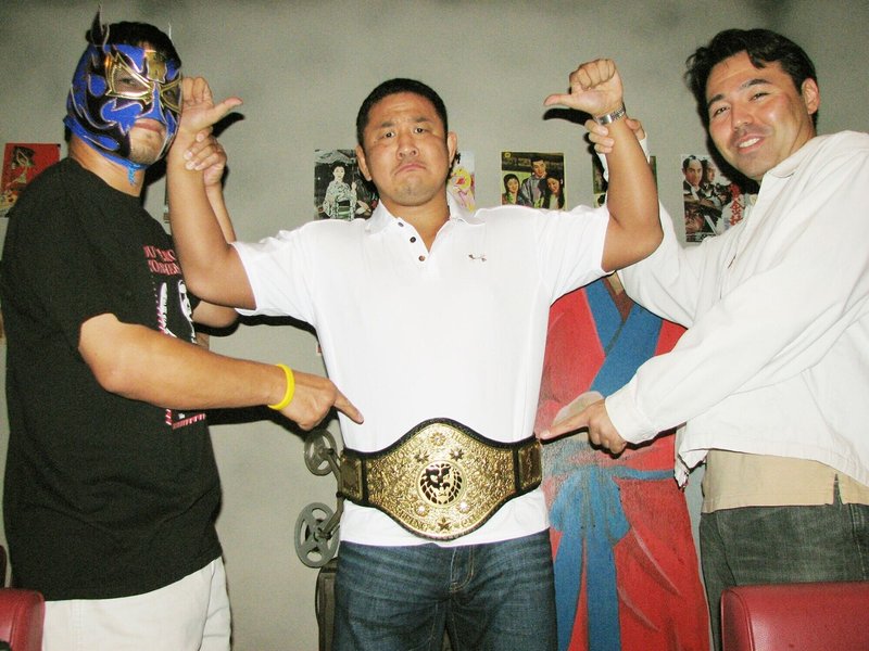 謎のチャンピオンベルトを巻かれ困惑する永田、左はカシン、右はサイモン・ケリー（０８年８月、東京・新宿の猪木酒場）