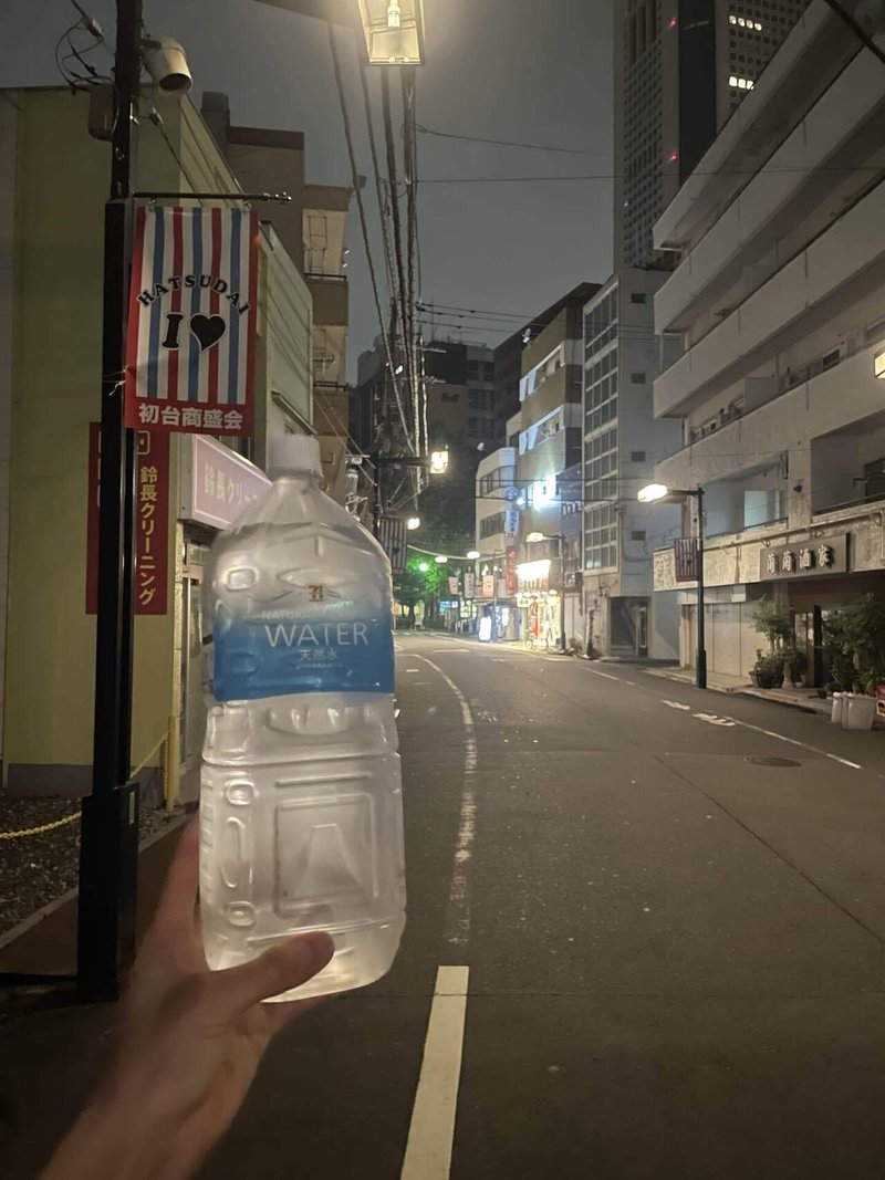 夜の道を歩きながら手に持ったペットボトルを撮った写真